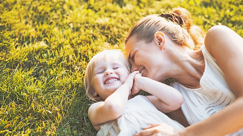 Happy mother and baby laying on meadow