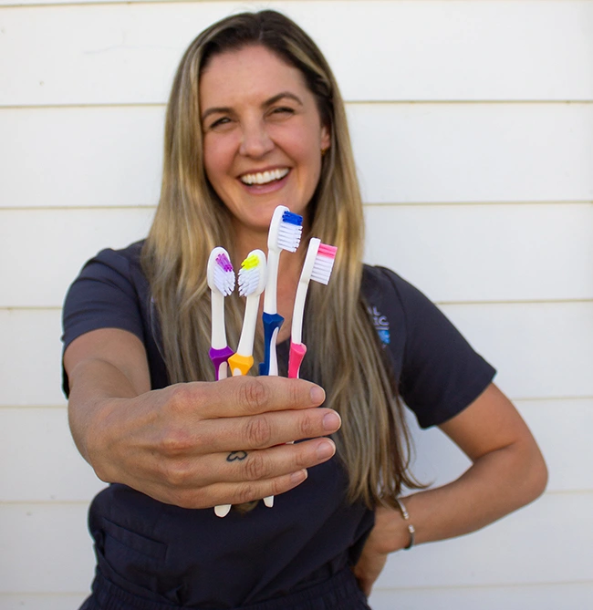 Team Member holding a handful of colorful toothbrushes